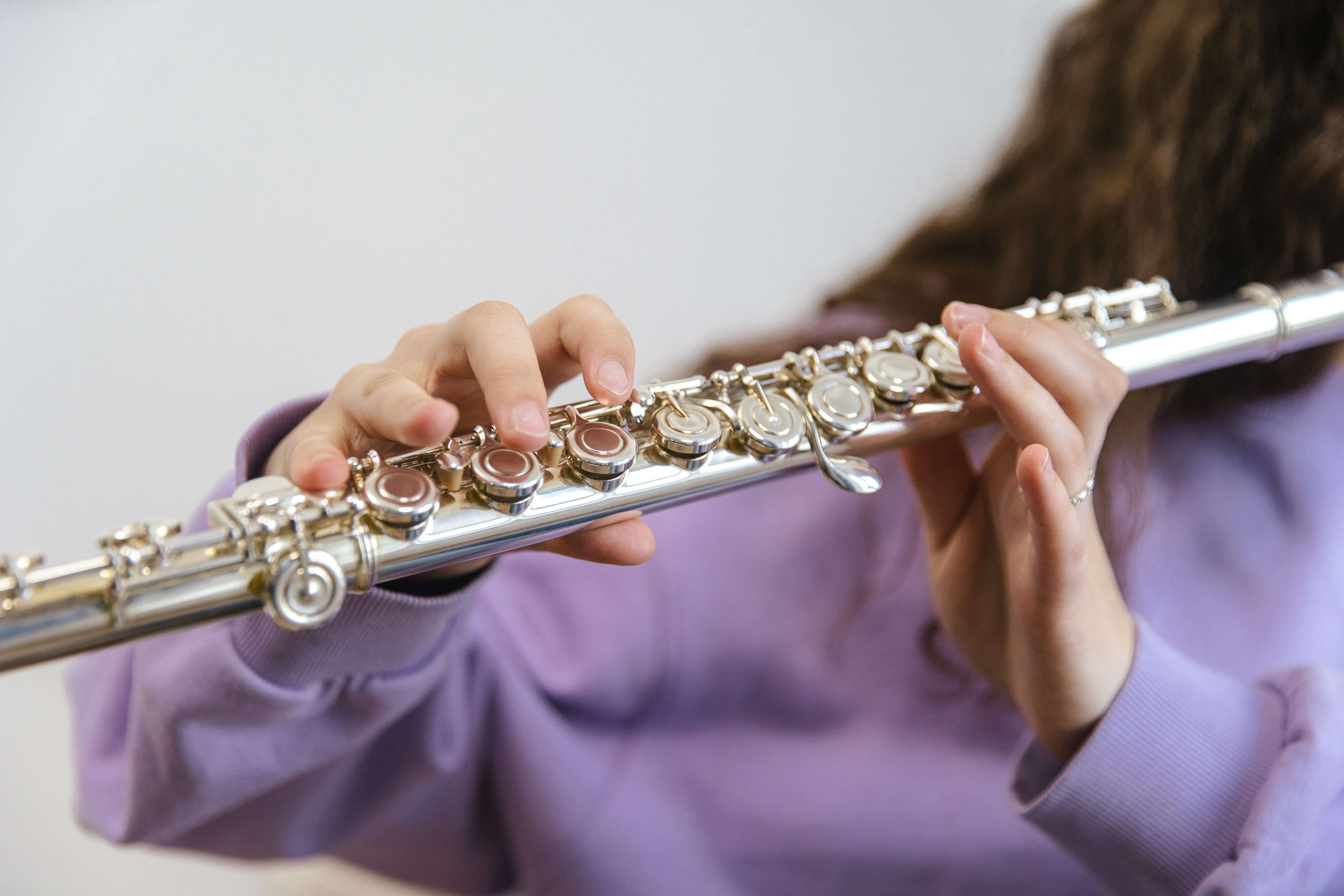 Person Holding Silver Flute in Blue Textile